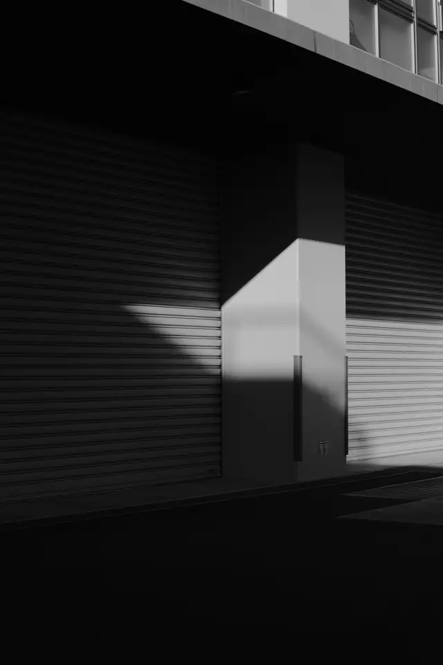 Cortinas metálicas cerradas en una fachada comercial, luz y sombra